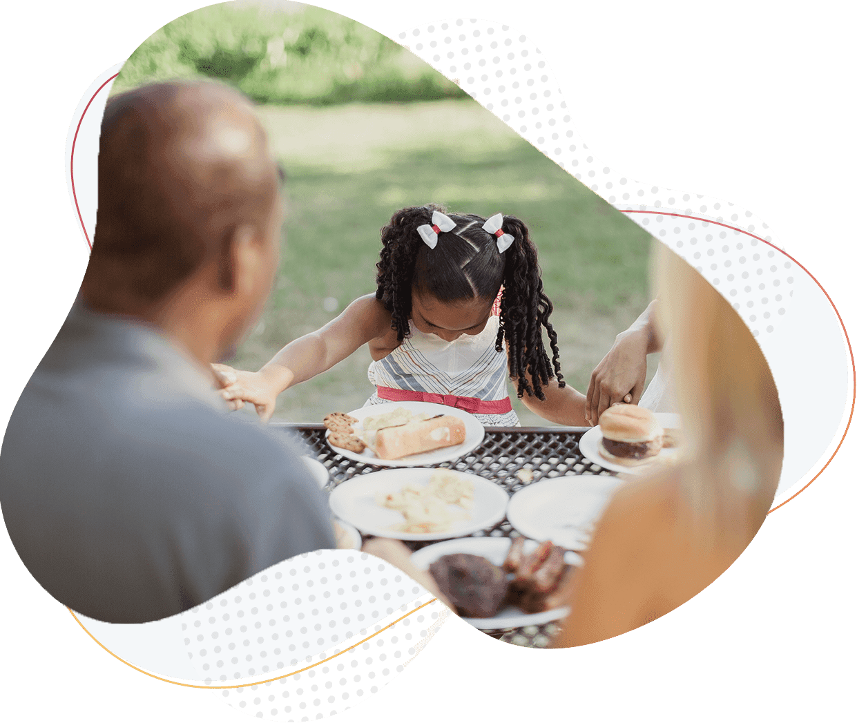 girl praying at a meal with her family