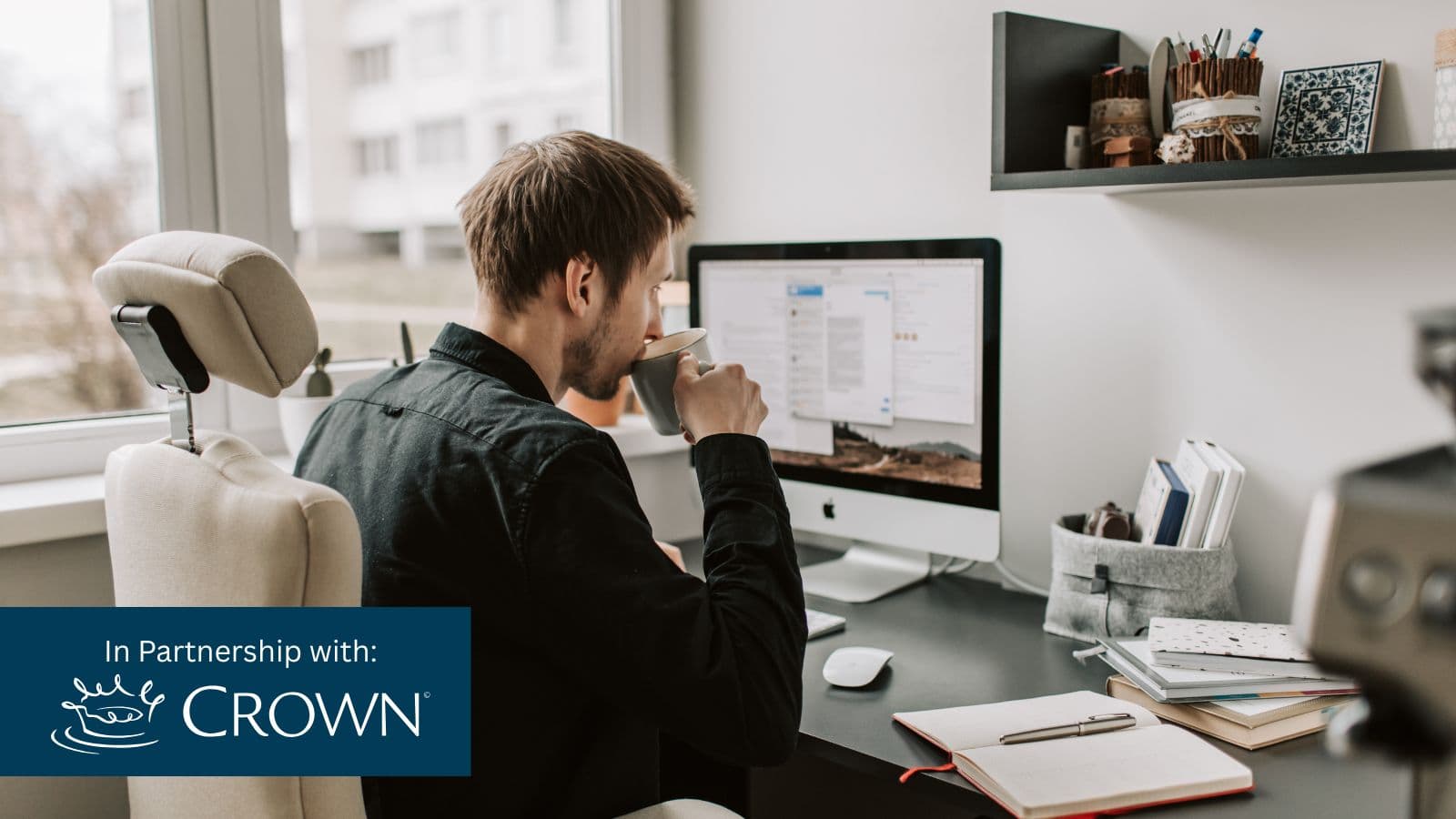 person sitting at desk with cup of coffee and blue rectangle in lower left corner with text In Partnership with: Crown