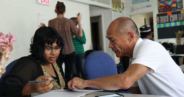 Asian Man tutors black woman at round table