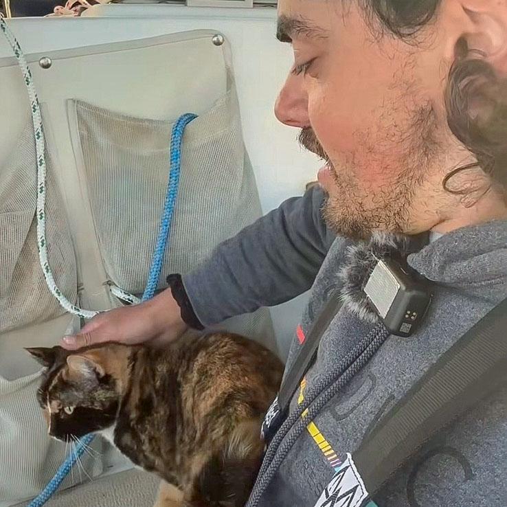 Widger pets his cat, Phoenix, on their sailboat somewhere in the Pacific Ocean as both make their way from Oregon to Hawaii