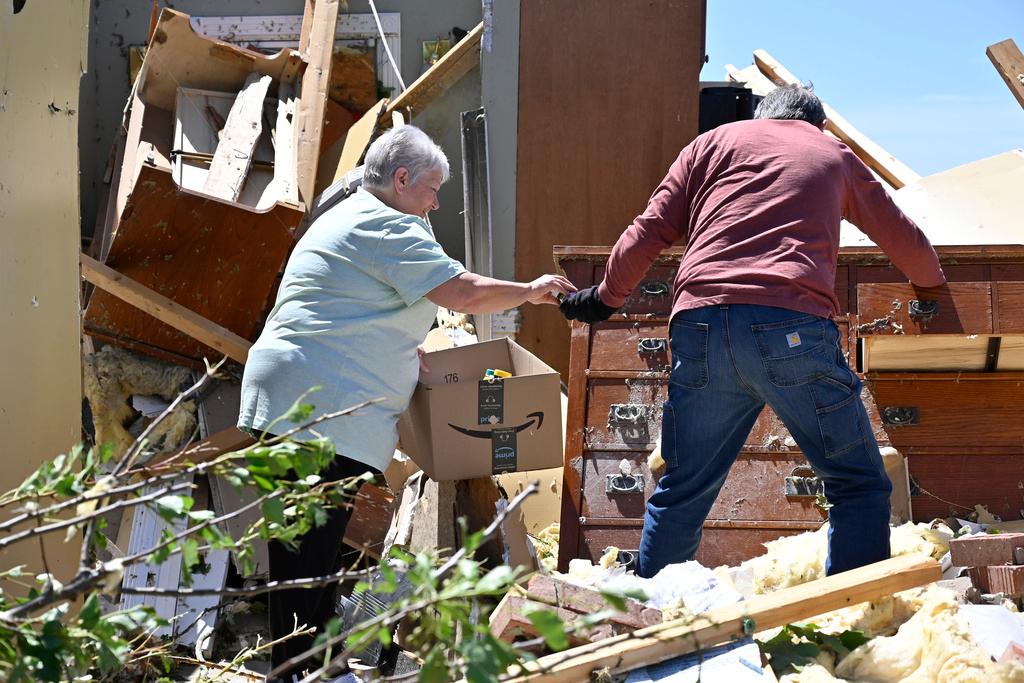 Don Allen, right, hands Doris Hensley medication that they are retrieving from the remains of her home following severe weather last night in London, Ky