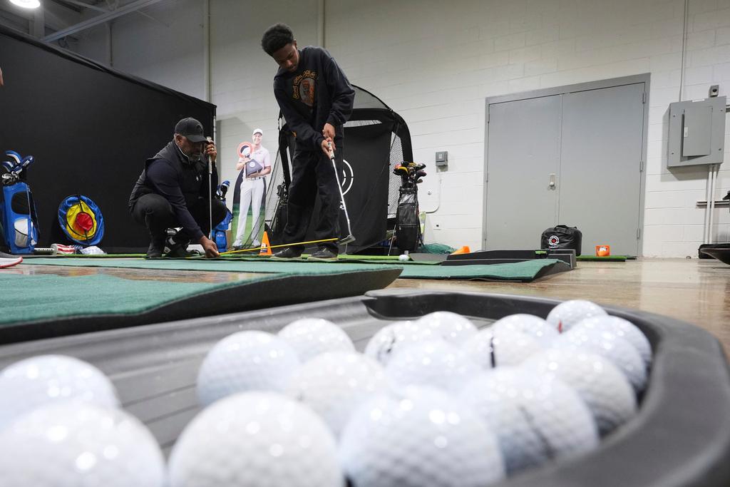 Shaun Horne, 16, a junior at Renaissance High School works on putting with golf coach Jess Hawkins in Detroit