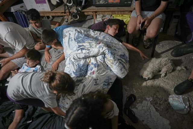 Israeli families take shelter during air raid sirens warning of incoming strikes by Iran, in Bnei Brak, near Tel Aviv