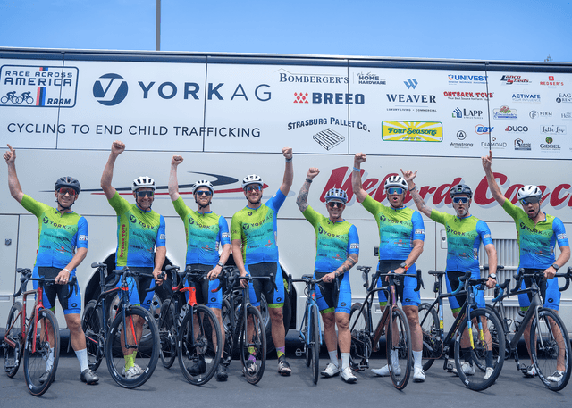 8 cyclists holding their fists into the air, with the other hand steadying the bicycles that just carried them to first place 