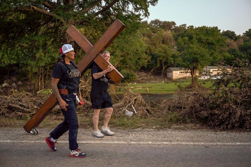 Disaster relief chaplain Sandi Gilmer, left, and Dan Beazley search for a permanent place for Beazley's large cross in memory of flooding victims near Camp Mystic in Hunt, Texas