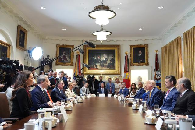 President Donald Trump during a cabinet meeting at the White House, with historic images behind him