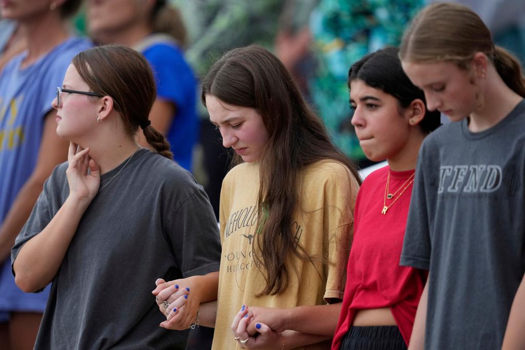 People hold hands during a vigil for flooding victims at Tivy Antler Stadium in Kerrville, Texas