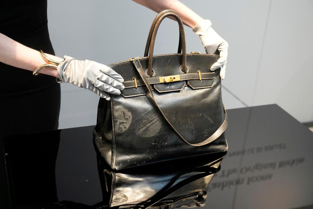 An auction officer displays the original Birkin bag created by Hermès for Jane Birkin in 1984