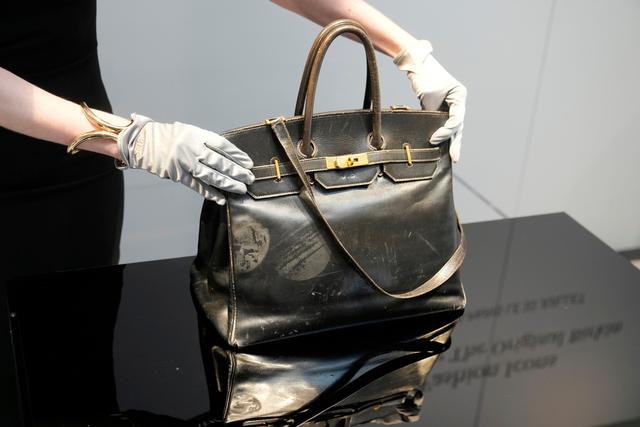 An auction officer displays the original Birkin bag created by Hermès for Jane Birkin in 1984