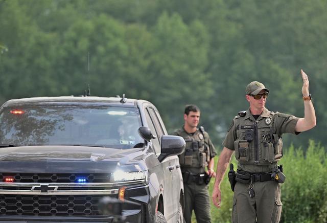 Police officers block the street leading to where two Pennsylvania state troopers were ambushed and shot