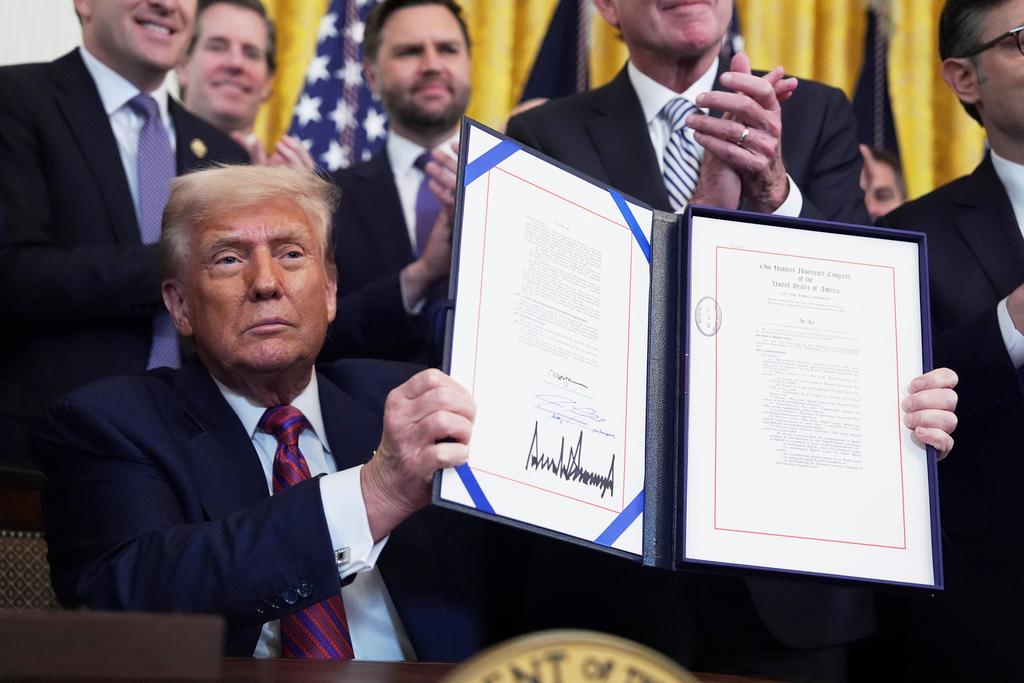 President Donald Trump holds up the signed document after signing the GENIUS Act, a bill that regulates stablecoins, a type of cryptocurrency, in the East Room of the White House