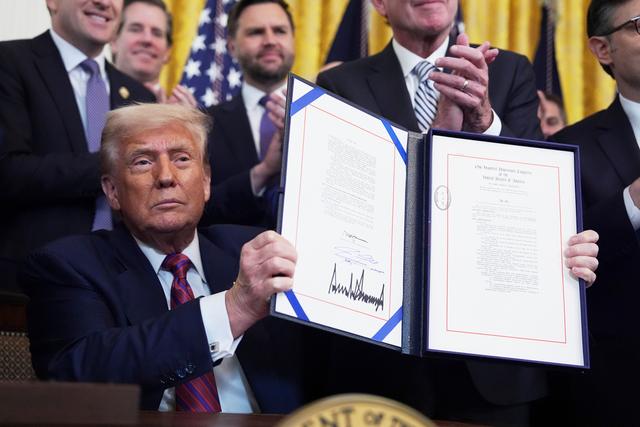 President Donald Trump holds up the signed document after signing the GENIUS Act, a bill that regulates stablecoins, a type of cryptocurrency, in the East Room of the White House