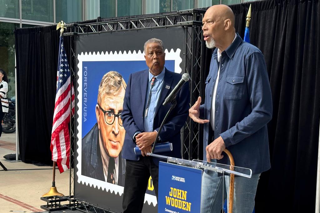 Jamaal Wilkes, left, listens as Kareen Abdul-Jabbar speaks at the first-day-of-issue ceremony for the John Wooden forever stamp on the UCLA campus in Los Angeles