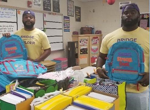 Two men holding school supplies