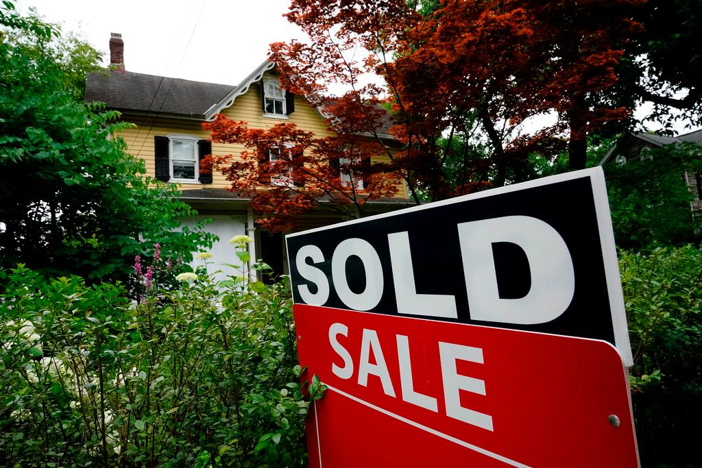 A sale sign stands outside a home