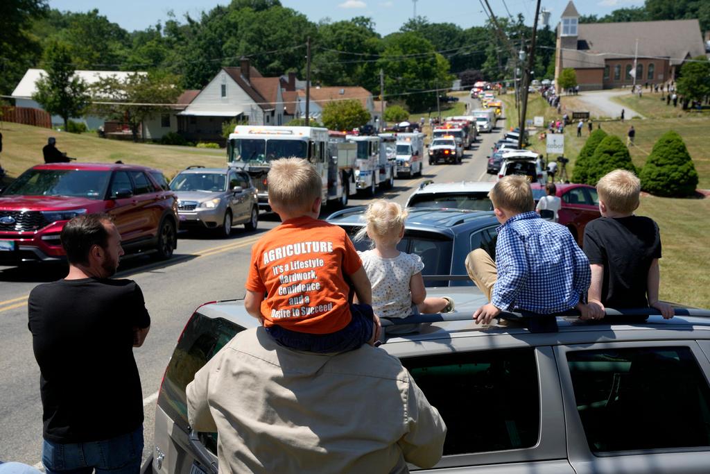 People watch as a procession of fire trucks follows a Saxonburg, Pa. fire truck carrying the casket of Cory Comperatore, following a memorial service at Cabot United Methodist Church