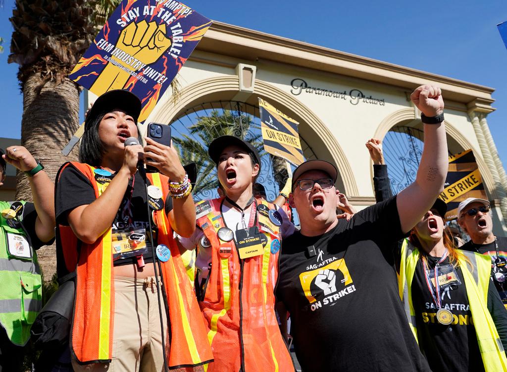 SAG-AFTRA captains Iris Liu, left, and Miki Yamashita, center, and SAG-AFTRA chief negotiator Duncan Crabtree-Ireland lead a cheer for striking actors outside Paramount Pictures studio
