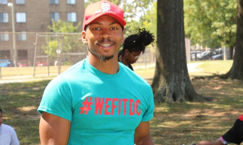 Man in teal shirt, red hat outdoors