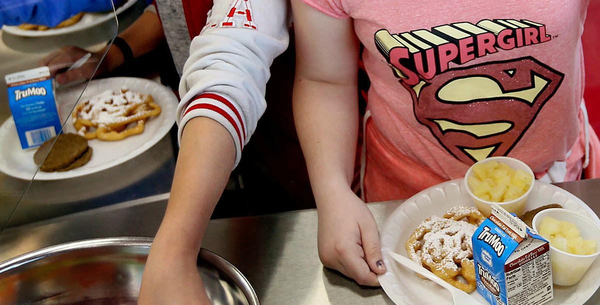Two school aged children with school lunches, desserts