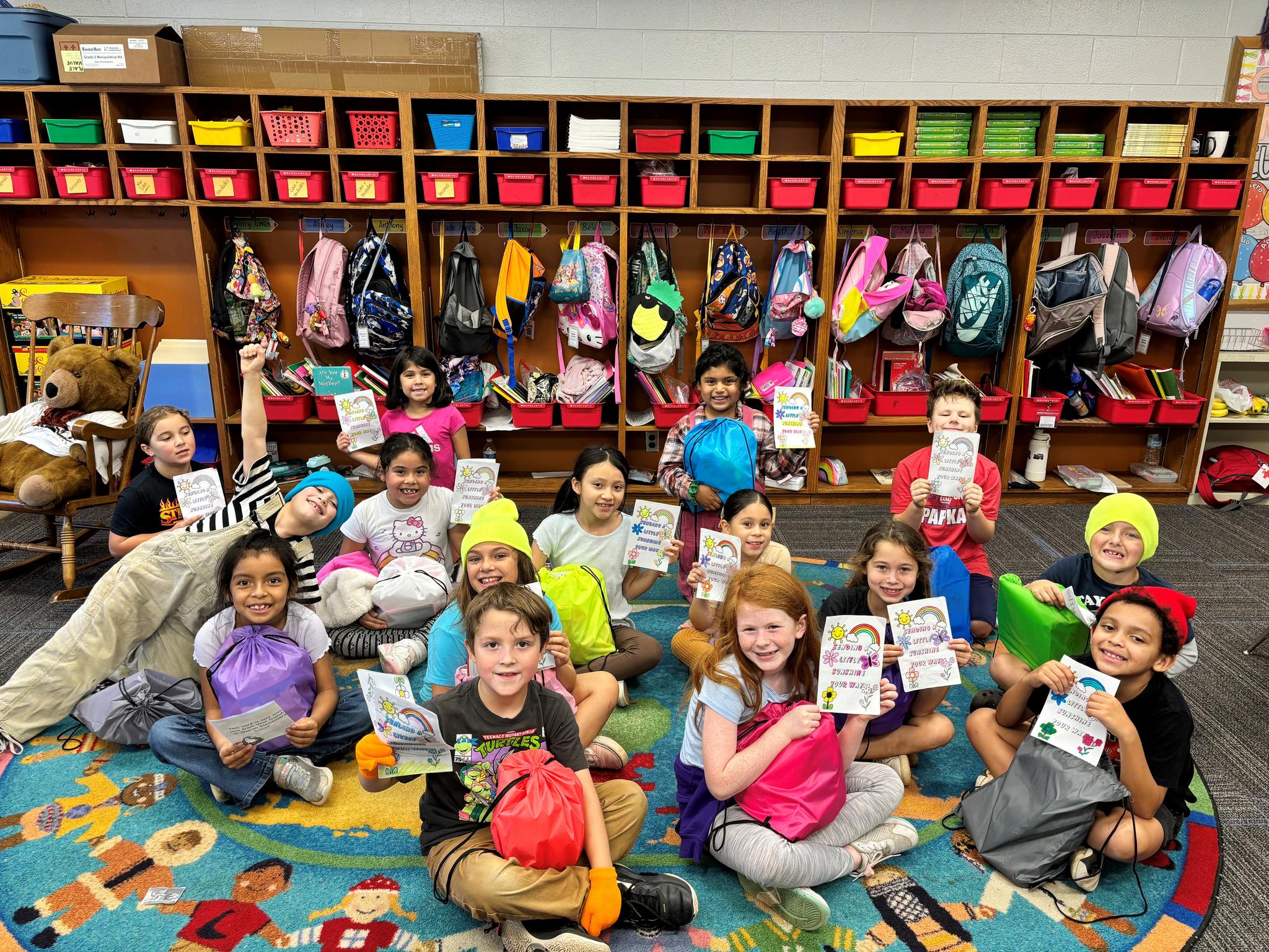 Elementary students showing off their For Kids By Kids care packages.