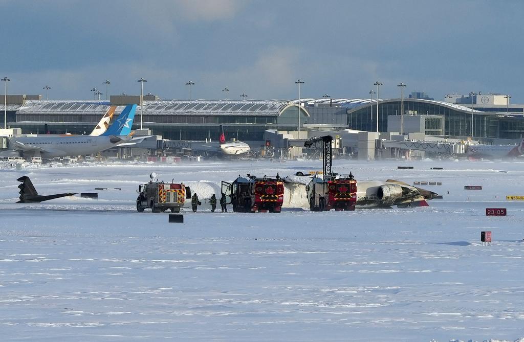 Pearson International Airport firefighters work on an upside down Delta Air Lines plane, which was heading from Minneapolis to Toronto when it crashed on the runway, in Toronto