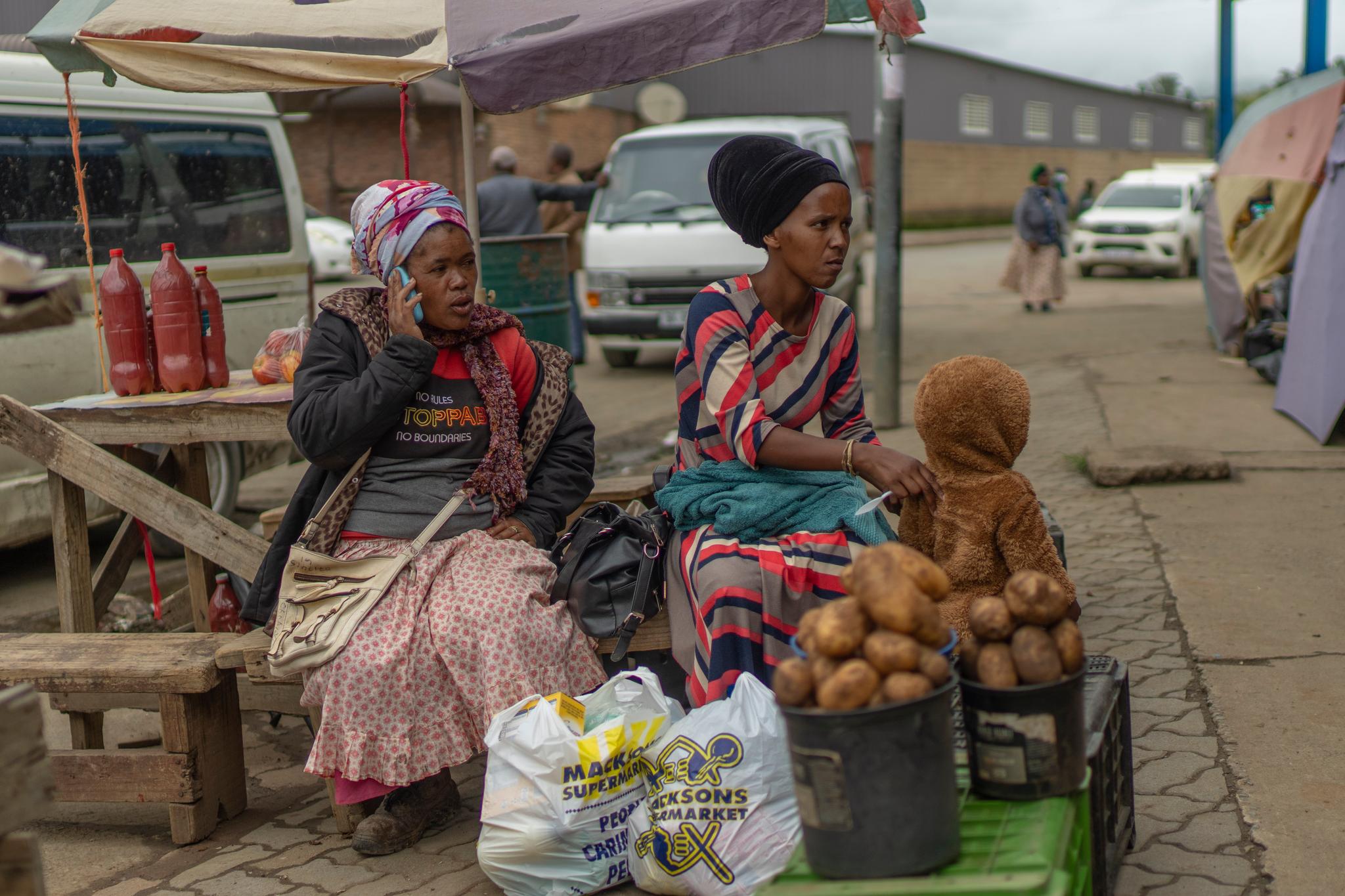 Women with potatoes and a small child side of the road.