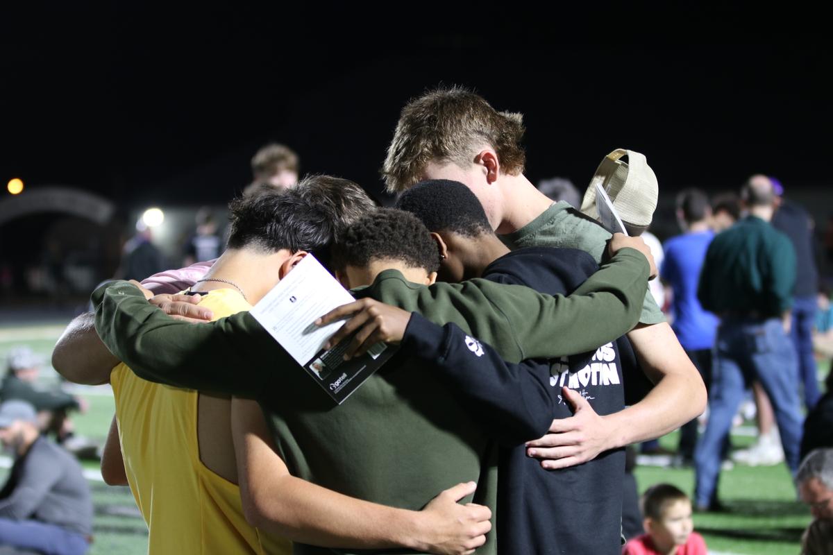 Five young men, praying in a huddle