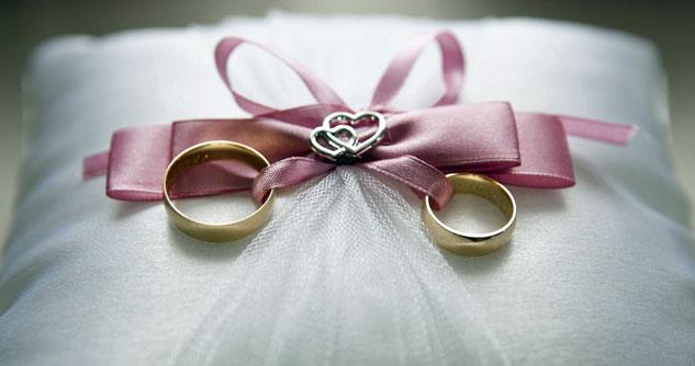 Wedding rings tied to a pillow with a pink bow, silver hearts in the middle