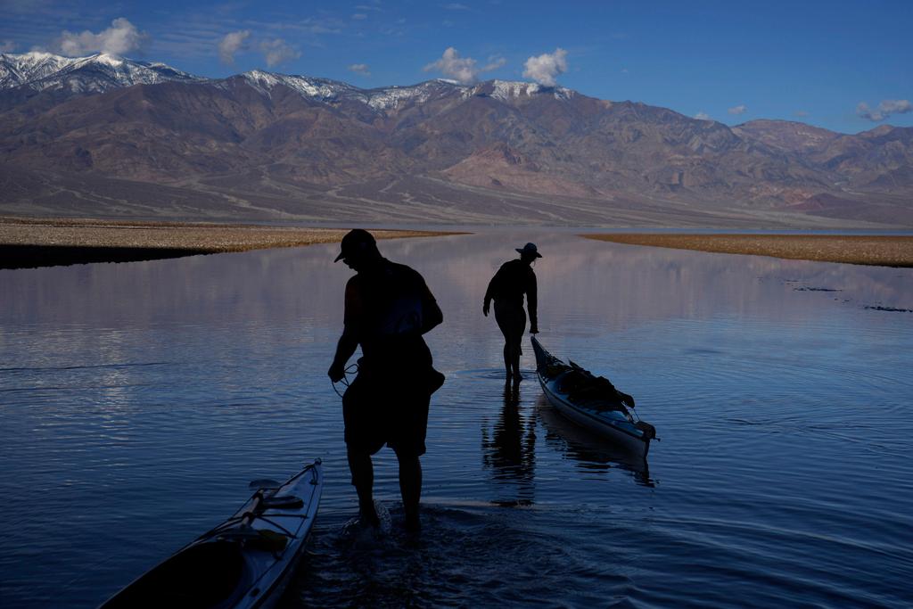 Two people pull kayaks into water at Badwater Basin in Death Valley National Park in California