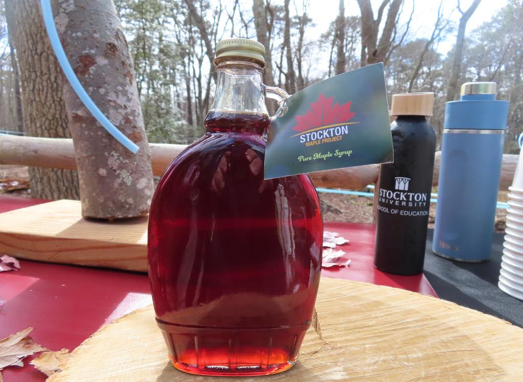 A bottle of maple syrup produced by Stockton University's Maple Project sits an an outdoor table at the university's Galloway, N.J. campus on Feb. 21, 2024. 